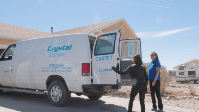 Two women-professional cleaners close the back of the Crystal Clean work van